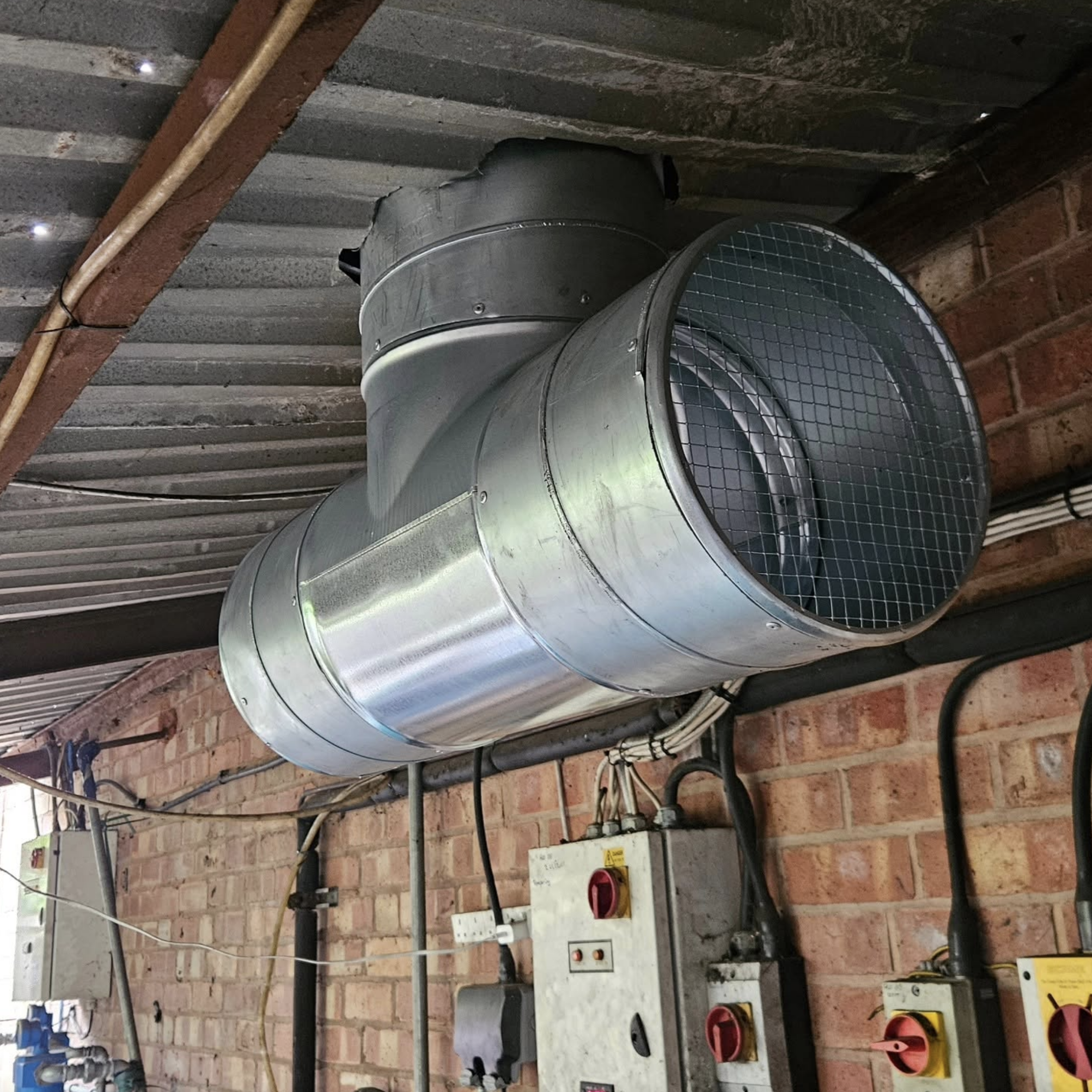 Commercial extract fan and control panels in an industrial plant room
